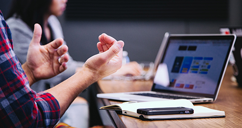 Hands gesturing in front of computer